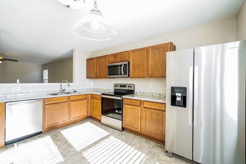 A kitchen with wooden cabinets and a stainless steel refrigerator.