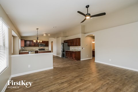 A spacious living room with a ceiling fan and hardwood floors.