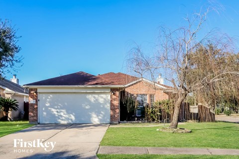 a brick house with a garage and a tree in the yard