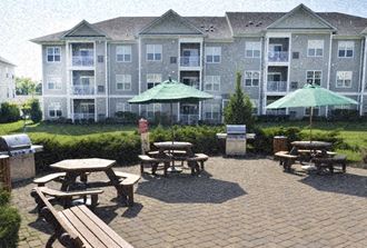 a patio with benches and umbrellas in front of an apartment building