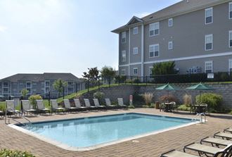 a swimming pool with chairs and a building in the background