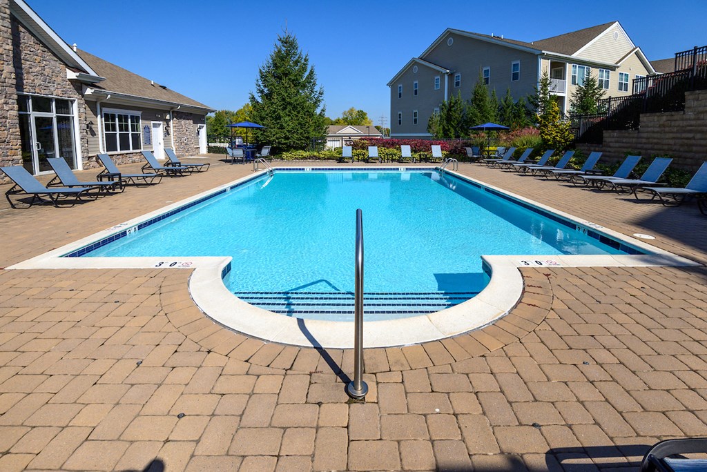 a swimming pool with chairs around it in front of a building