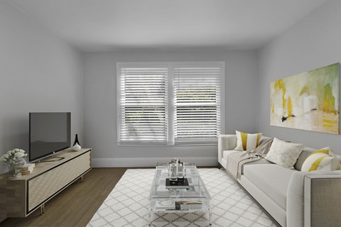 A living room with a white couch, a coffee table, and a television.