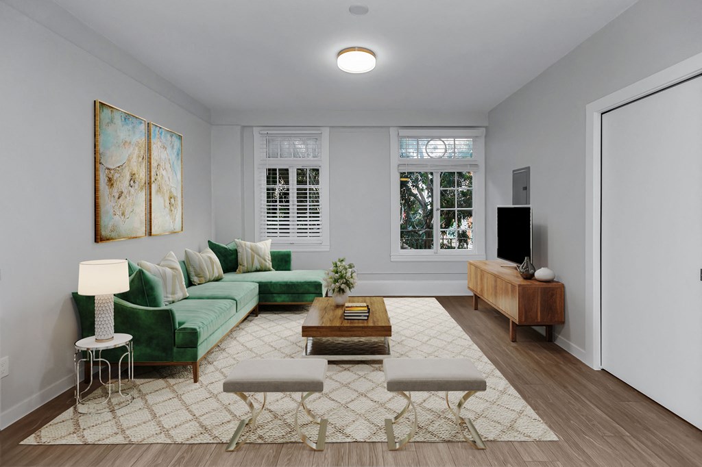 A living room with a green couch, a coffee table, and a painting on the wall.