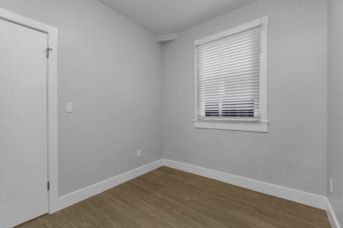 A room with a white door and a window with blinds.