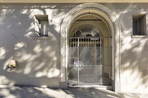 A white building with a large arched doorway and a metal gate.