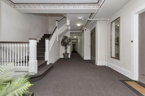A long hallway with a staircase on the left and a door on the right.