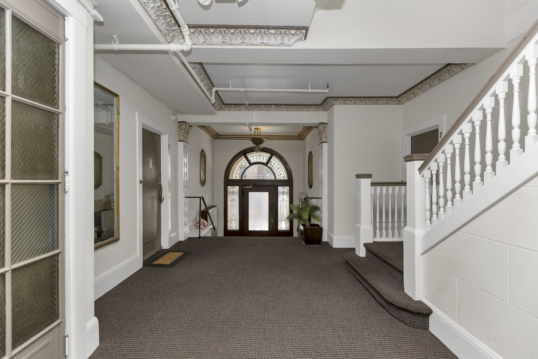 A long hallway with a staircase on the right and a door on the left.