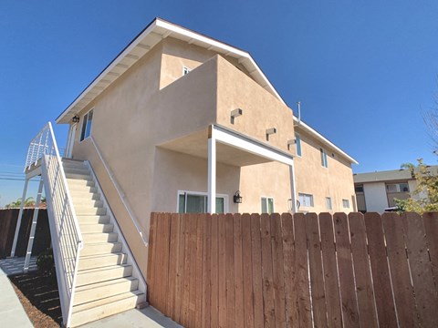 the front of a house with a wooden fence and stairs