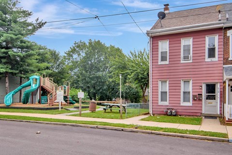 a pink house with a playground on the corner of a street