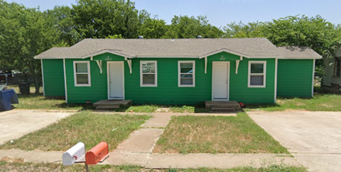 A green house with a white door and windows.