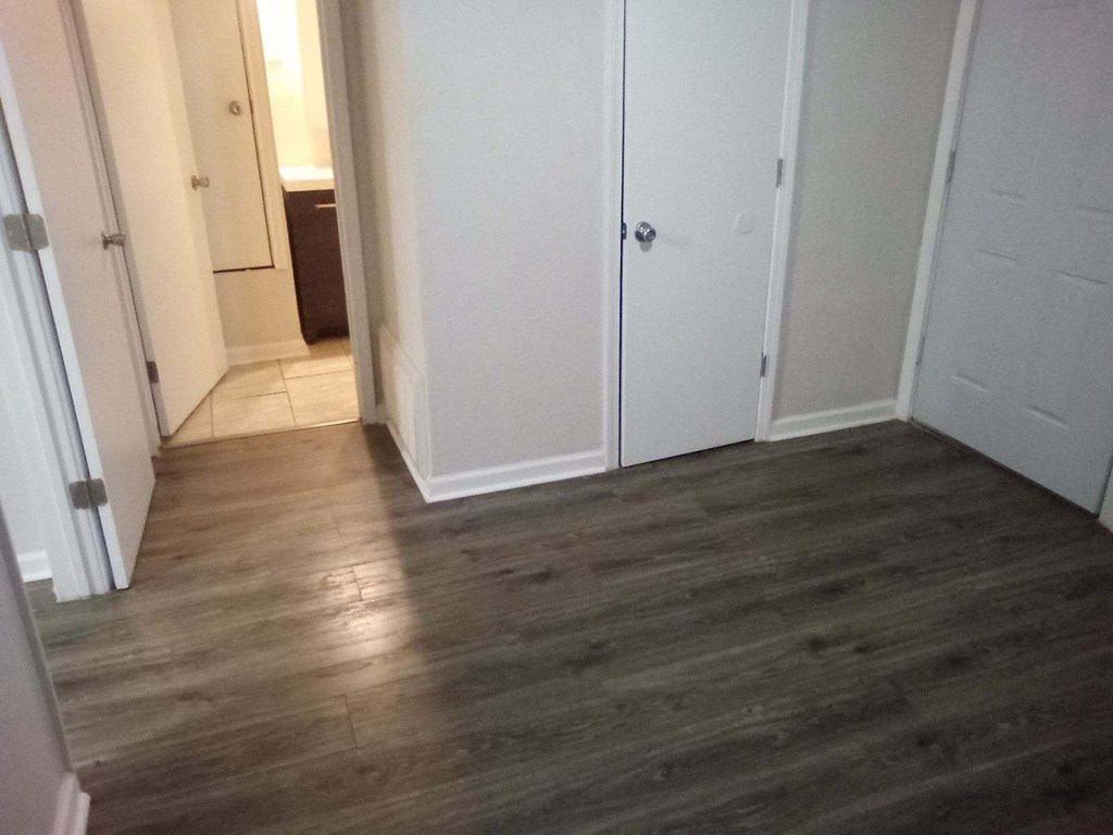 a room with wooden floors and white closets