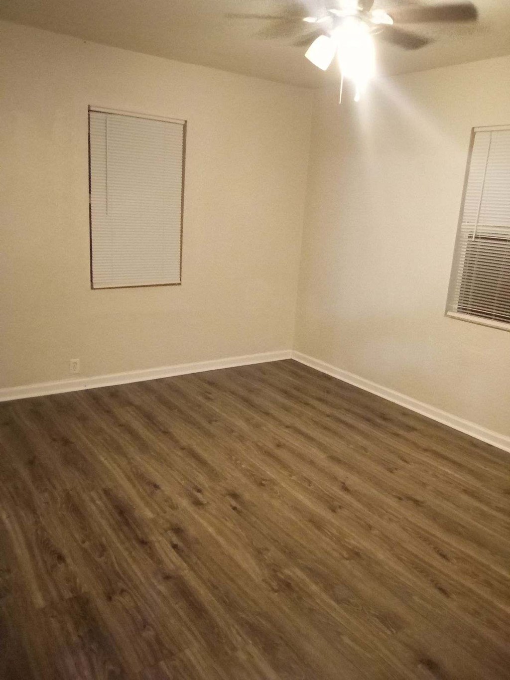 an empty room with wooden floors and a ceiling fan