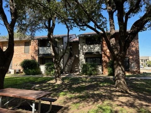 an apartment building with a picnic table in the yard