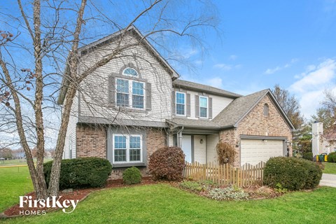 A house with a well-maintained lawn and a fence in front.