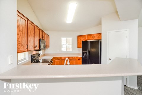 A kitchen with wooden cabinets and a black refrigerator.