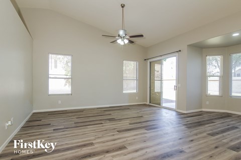 the spacious living room with wood flooring and a ceiling fan