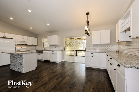 A modern kitchen with white cabinets and a wooden floor.