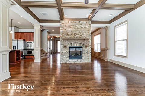 A spacious living room with a stone fireplace and wooden floors.