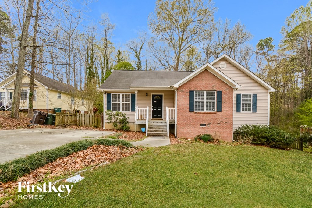 A house with a brick facade and green shutters is for sale.