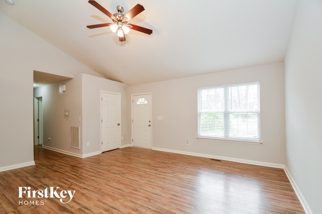 A room with a ceiling fan and wooden floors.