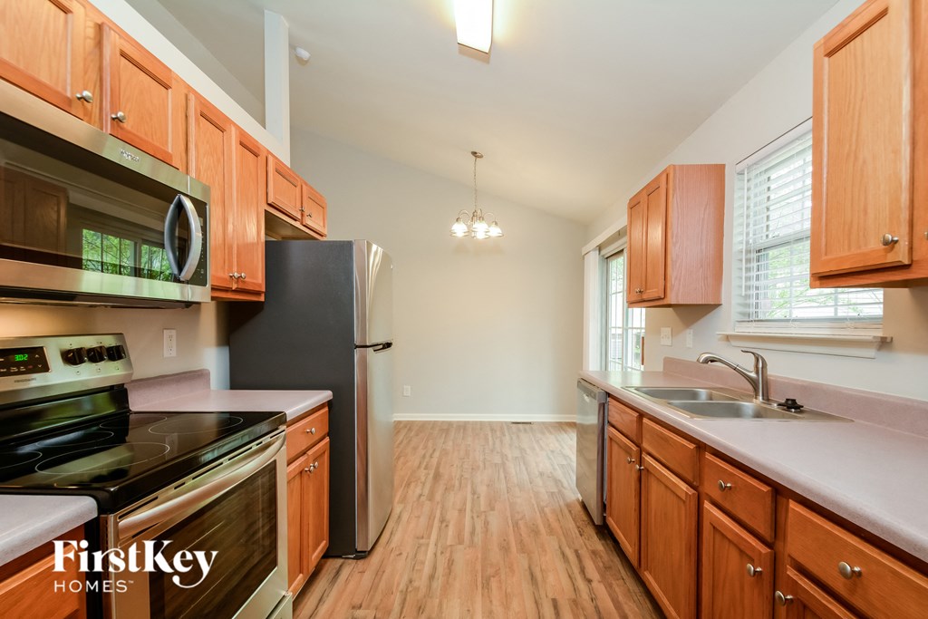 A kitchen with wooden cabinets and a black fridge.