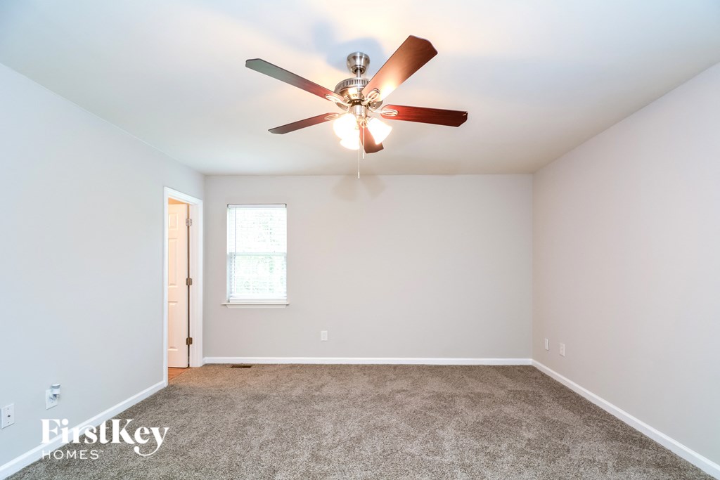A room with a ceiling fan and carpeted floor.