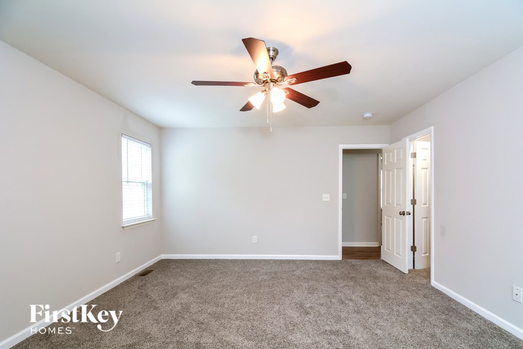 A spacious room with a ceiling fan and a door leading to another room.