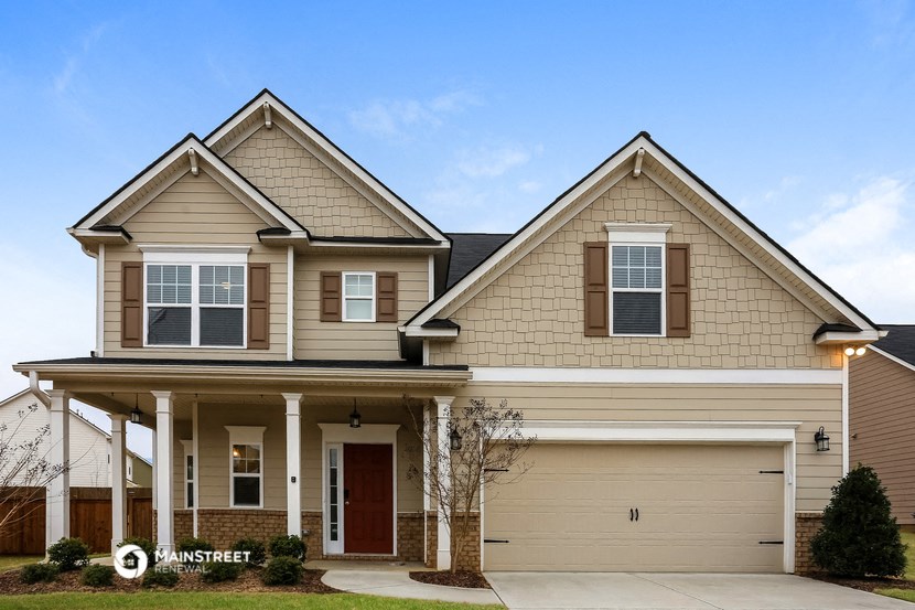 a beige house with a porch and a driveway