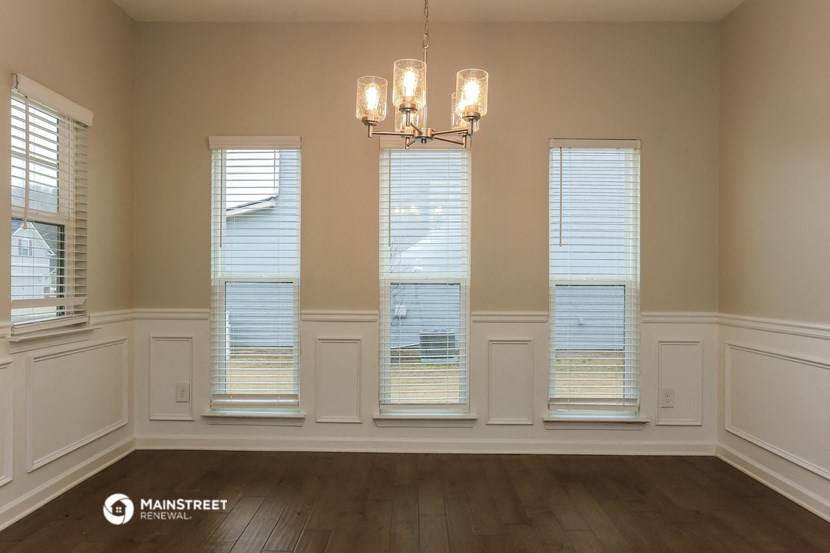 an empty dining room with three windows and a chandelier