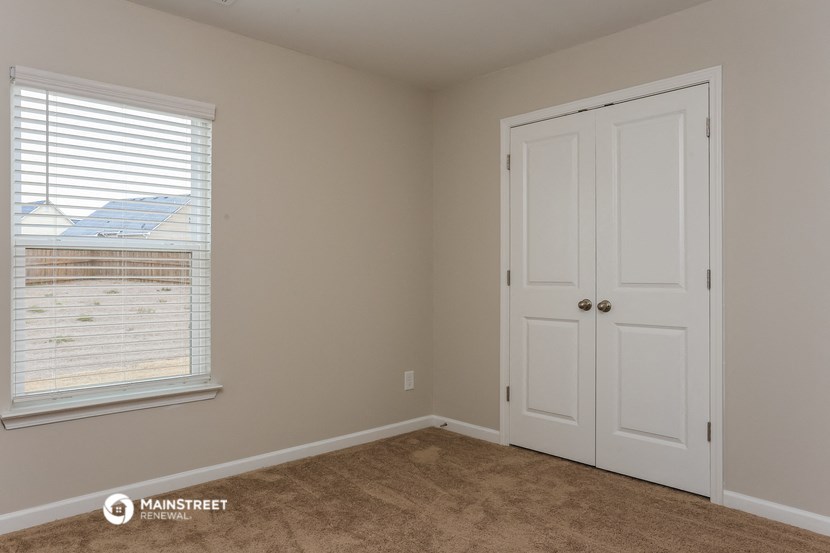 a bedroom with a door and a window and a carpeted floor
