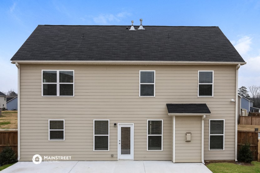 a tan house with a black roof and a driveway