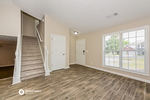 the living room of a house with a staircase and a large window