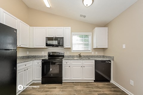 a kitchen with white cabinets and black appliances