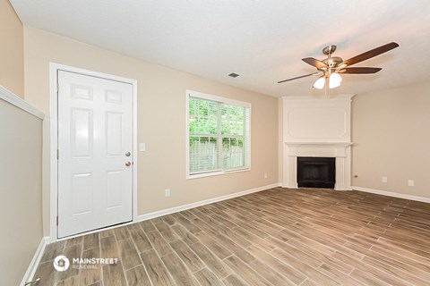 the living room of a house with a fireplace and a ceiling fan