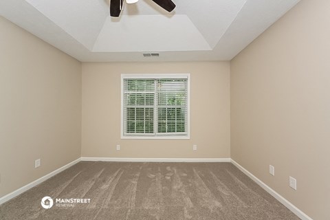 an empty room with a window and a ceiling fan