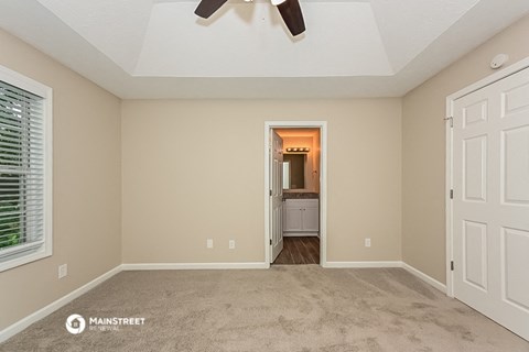 a spacious living room with carpet and a ceiling fan