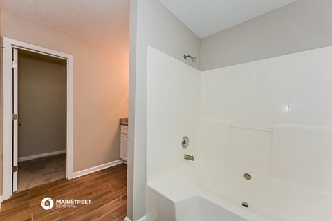 a bathroom with a large white tub and a door to a closet