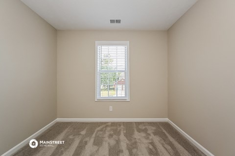a spacious room with carpet and a window