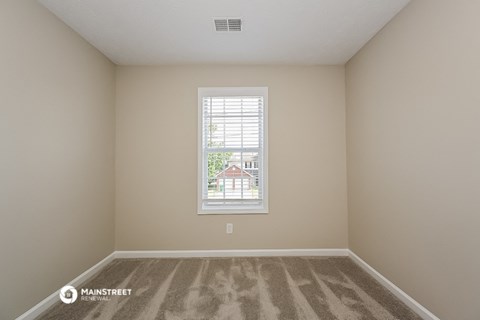 an empty room with a window and carpeting