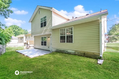 a backyard with a house and a ramp to a driveway