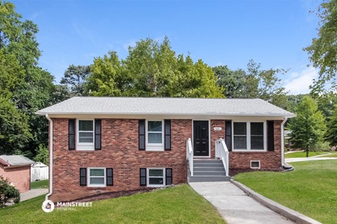 a red brick house with black shutters and a sidewalk