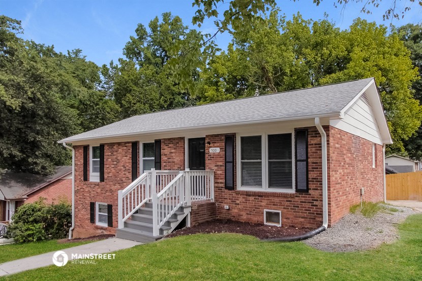 a small brick house with a porch and a white staircase