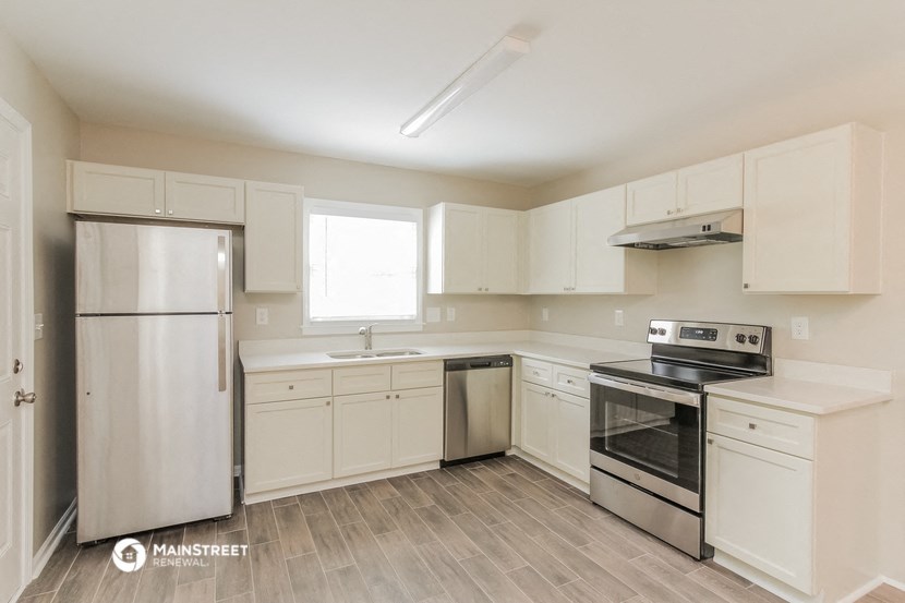 an empty kitchen with white cabinets and stainless steel appliances