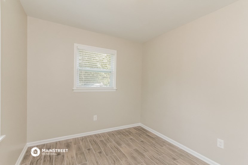 an empty room with wooden floors and a window
