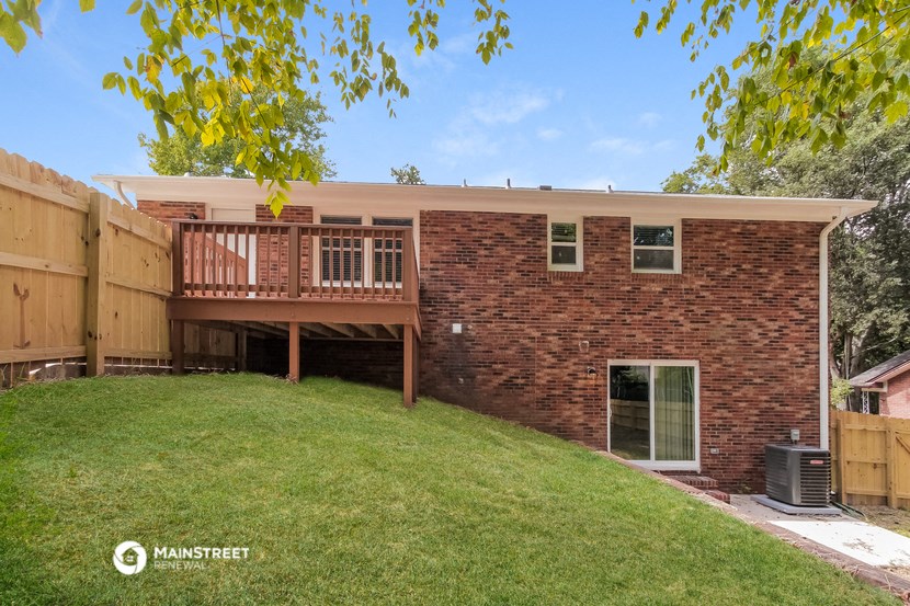 the back of a brick house with a yard and a deck
