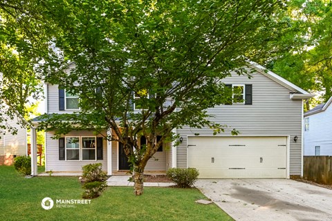 a white and gray house with a tree in the yard