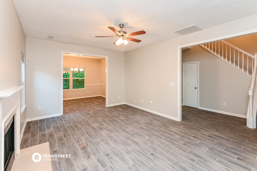 an empty living room with a ceiling fan and a staircase
