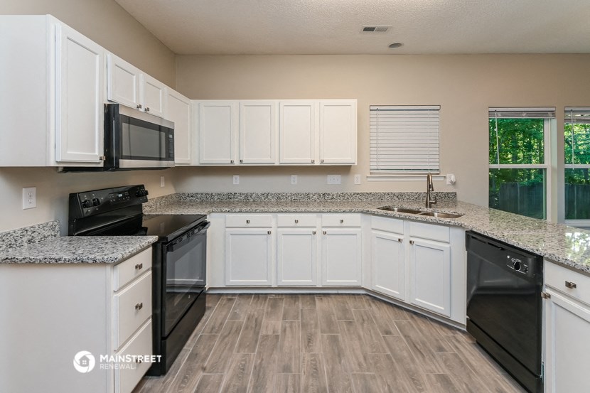 a kitchen with white cabinets and granite counter tops and black appliances
