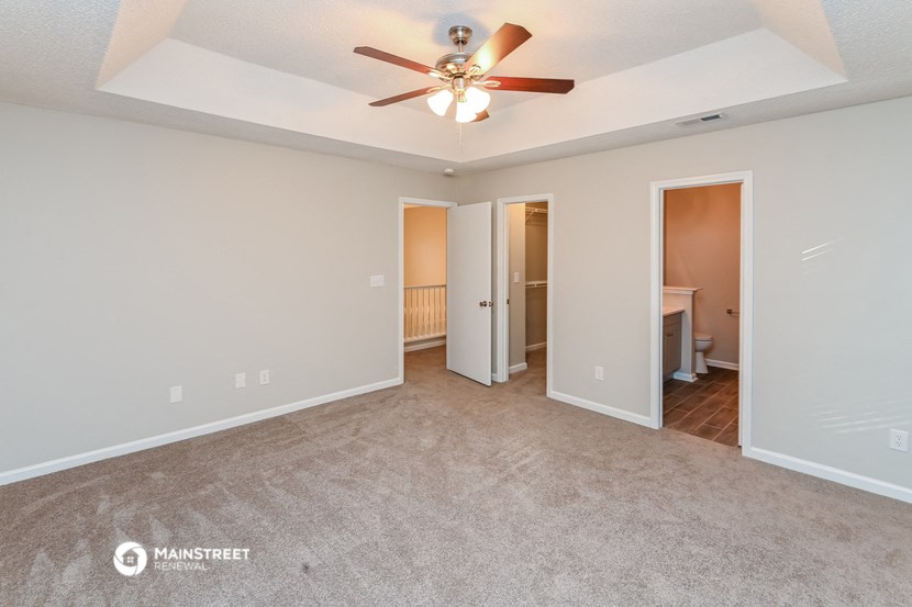 the spacious living room with carpet and ceiling fan